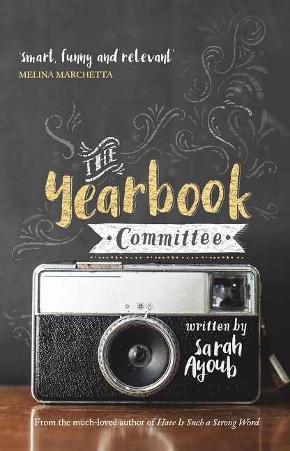 The Yearbook Committee — a 1970s style camera sits on a wooden surface